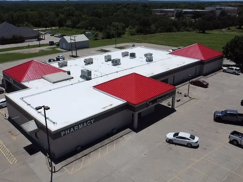 Commercial building with a white flat roof and red metal hip roofs