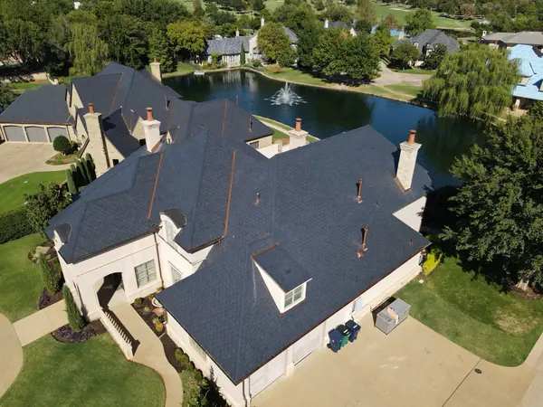 Aerial of a stucco lakefront home with an EcoStar roof and copper vents