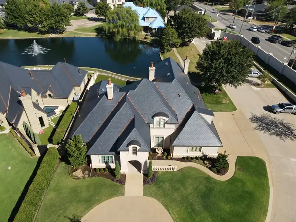Front aerial of a stucco home with an EcoStar slate roof and copper eyebrow dormers