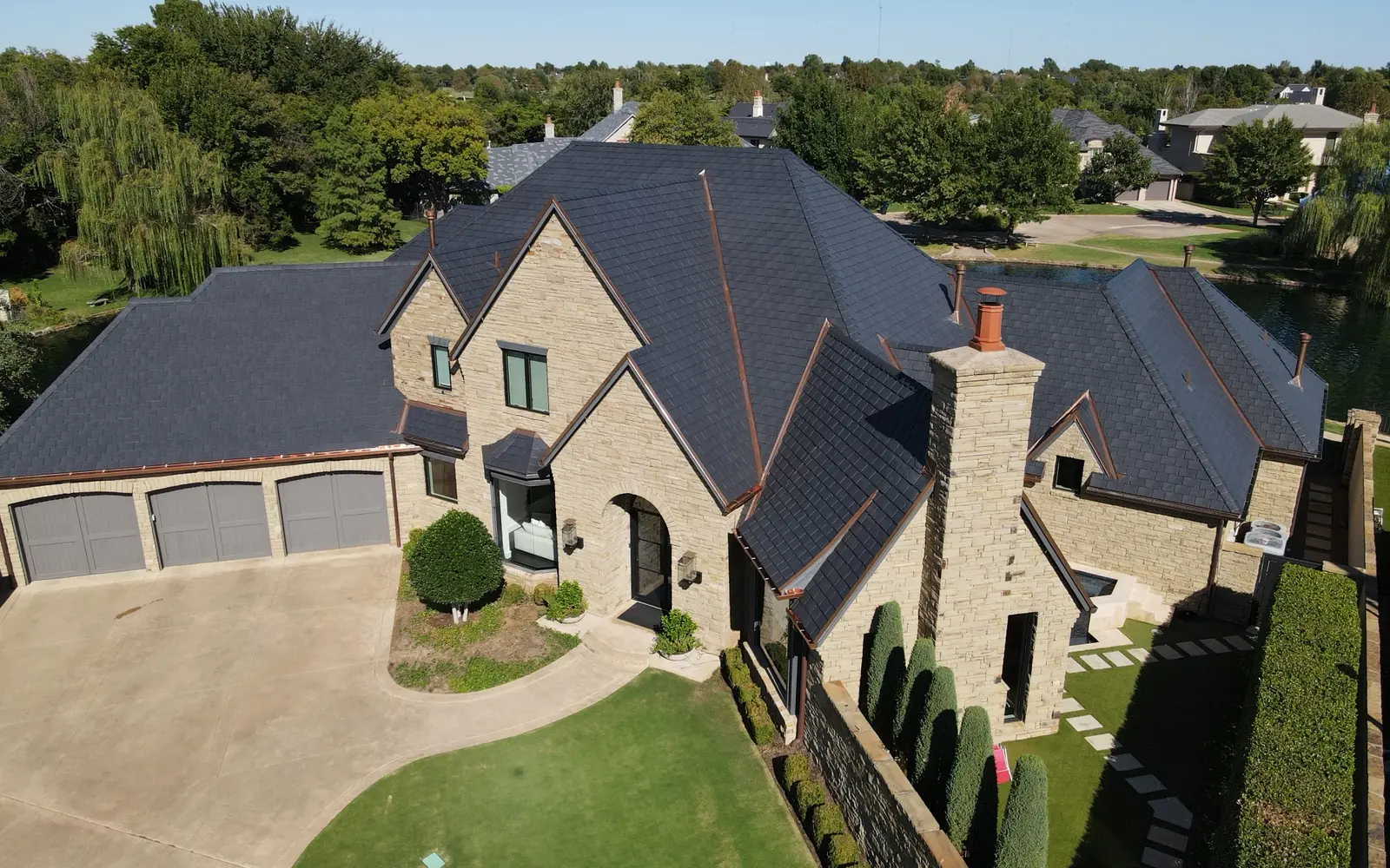 Stone lakefront home with an EcoStar synthetic slate roof and copper valleys
